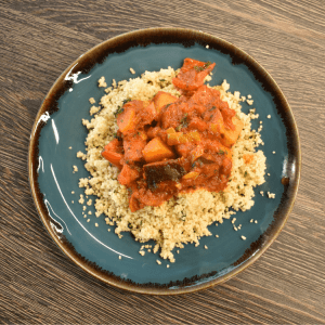 vegetable tagine on top of cous cous on a blue plate